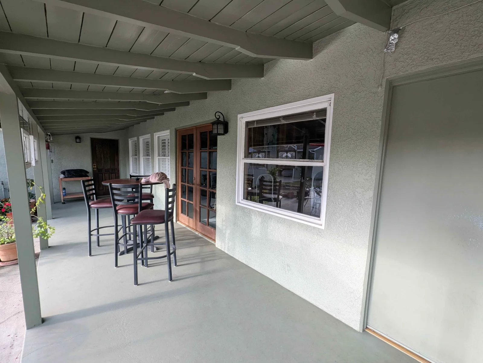 Covered patio with cleaned windows and French doors, bistro table and chairs