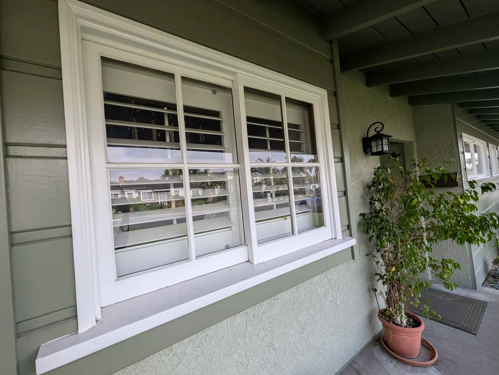 Close-up of a divided-light window with shutters after cleaning, wood frame and sill spotless