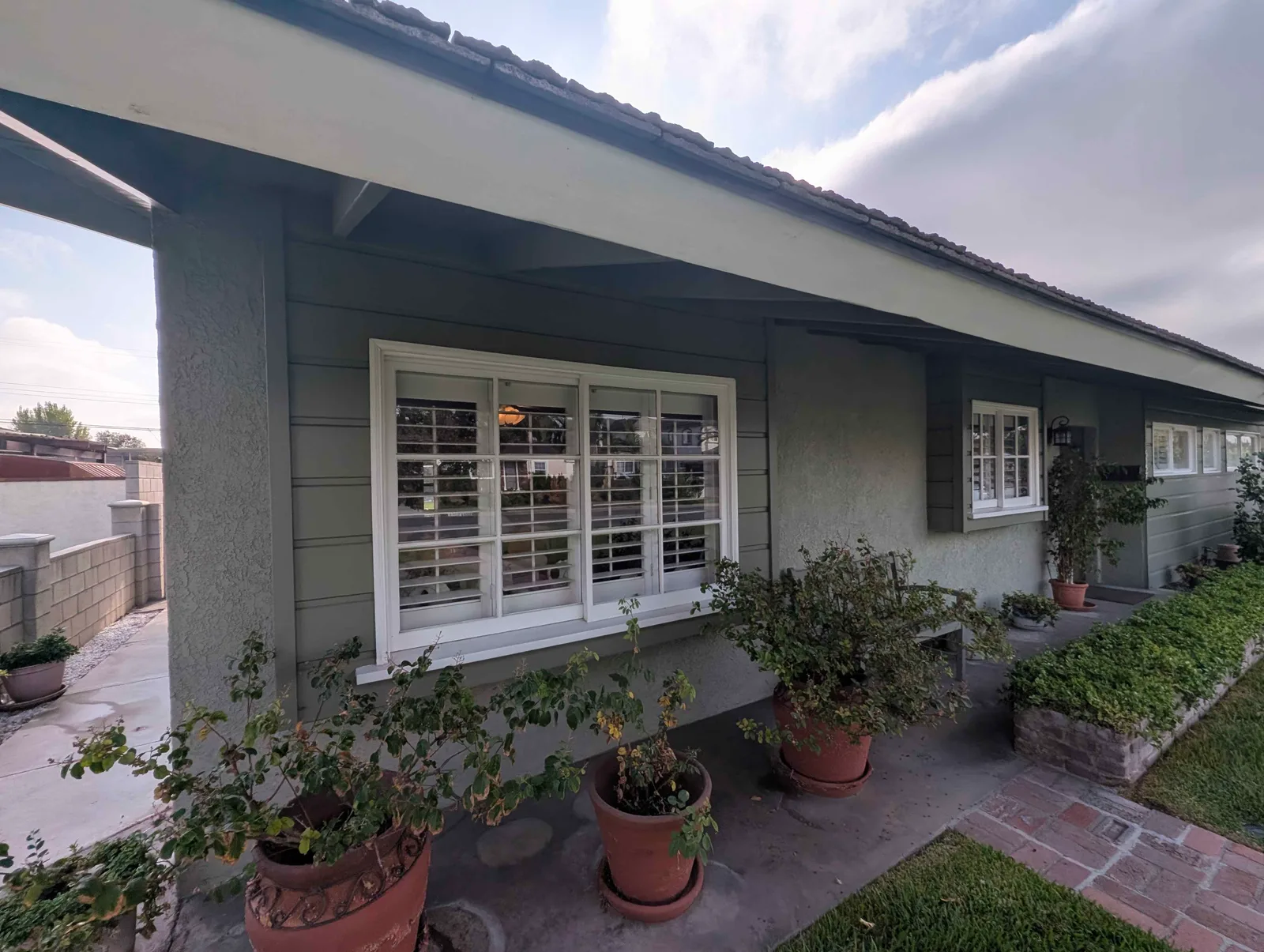 Front window with white plantation shutters after exterior cleaning, single-story stucco home, San Gabriel Valley