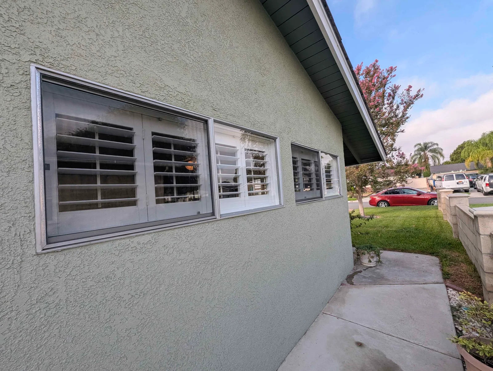 Side windows with louvered shutters after exterior cleaning, aluminum frames