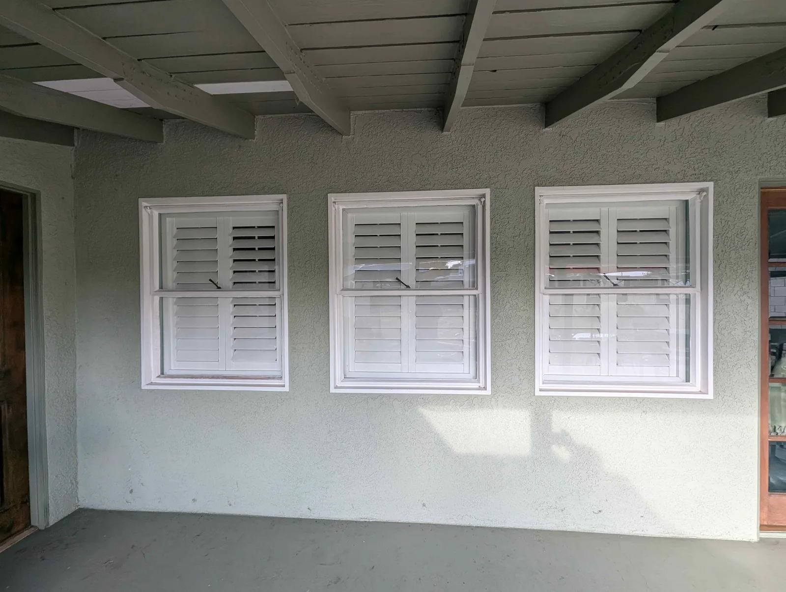 Three shuttered windows under a covered patio after cleaning